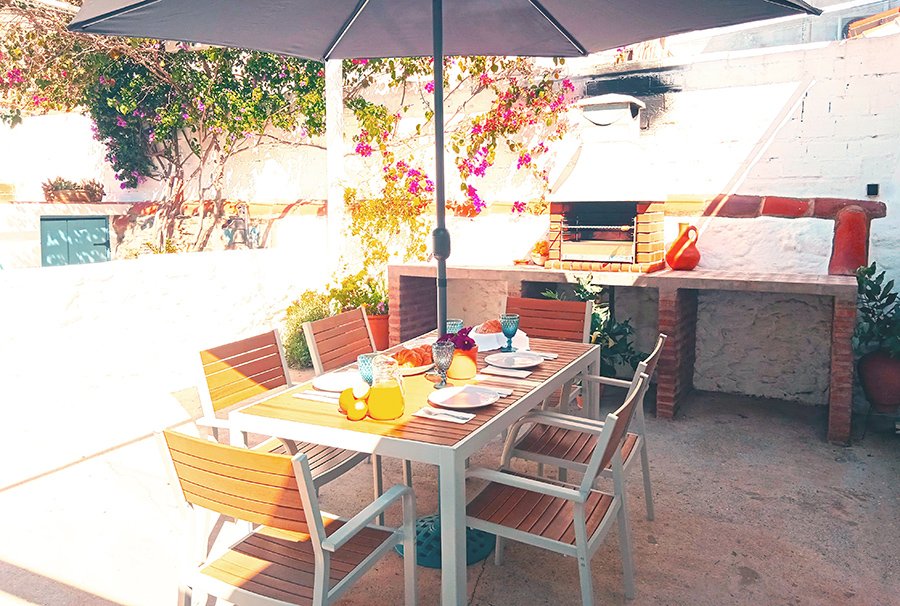 Imagen de terraza con mesa y sillas junto a la barbacoa